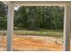 A backyard view from the covered porch with natural trees surrounding the property and orange clay soil at 575 Red Monarch Way, Moncks Corner, SC 29461