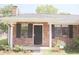 Charming brick home with a cozy front porch, black shutters, and manicured landscaping at 7712 Corley Dr, North Charleston, SC 29418