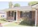 Quaint brick home featuring black shutters, fresh landscaping, and a welcoming front entrance at 7712 Corley Dr, North Charleston, SC 29418