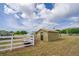 View of a new shed and chicken coop with a white fence and blue skies at 7875 Berry Manor Ln, Edisto Island, SC 29438
