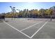 Well-maintained tennis court with a dark surface, surrounded by fencing and trees at 112 Riviera Dr, Summerville, SC 29483