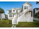 Beige two-story beach house with a staircase leading to a second-floor deck and manicured lawn at 1144 Clearspring Dr, Charleston, SC 29412