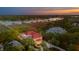 Beautiful waterfront home featuring a red roof, outdoor pool, lush landscaping, and breathtaking sunset views at 13 Broughton Rd, Charleston, SC 29407