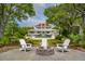 Spacious backyard featuring a fire pit, chairs, landscaping, pool and large white house in the background at 13 Broughton Rd, Charleston, SC 29407