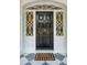 A stately black front door with ornate sidelights and a lion knocker welcomes guests to this luxurious home at 13 Broughton Rd, Charleston, SC 29407