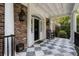 Charming front porch features checkered tile, a black rocking chair, and traditional lanterns for a welcoming entrance at 13 Broughton Rd, Charleston, SC 29407