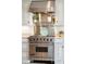 Close up of Viking range and stainless vent hood with stainless shelf and decorated countertops and white cabinets at 13 Broughton Rd, Charleston, SC 29407