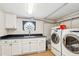 Functional laundry room features white cabinets, dark countertops, a decorative window, and a washer and dryer at 13 Broughton Rd, Charleston, SC 29407