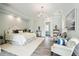 Bright main bedroom boasts chandelier, cool color palette and sitting area at 13 Broughton Rd, Charleston, SC 29407