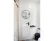 Modern bathroom with sleek white vanity, round mirror, and black fixtures against white paneled walls at 14 Paula Dr, Charleston, SC 29407