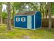 Charming blue storage shed with light-blue trim and a shingled roof, nestled among the trees at 14 Paula Dr, Charleston, SC 29407