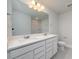 Well-lit bathroom with dual sinks, white cabinetry, quartz counters, and a large framed mirror at 154 Royal Cainhoy Way, Huger, SC 29450