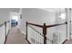 Upstairs hallway with hardwood railing overlooking the foyer with carpet and a chandelier at 2009 Terrabrook Ln, Charleston, SC 29412
