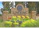 Lindera Preserve community entrance featuring a brick sign, lush greenery, and colorful flowers at 214 Squire Pope Rd, Summerville, SC 29486