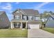 Two-story house with a brick and gray facade, a white garage door, and a well-manicured lawn at 214 Squire Pope Rd, Summerville, SC 29486