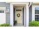 Inviting entryway featuring a decorative wreath on a cream-colored door with sidelights and potted plants at 3061 Cross Vine Ln, Summerville, SC 29483