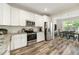 Open kitchen area with stainless appliances, white cabinets, granite countertops, and wood-look flooring at 3061 Cross Vine Ln, Summerville, SC 29483