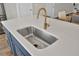 Close-up of the kitchen island with a stainless steel sink and brass faucet and white countertop at 3990 Hillyard St, North Charleston, SC 29405