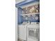 Well organized laundry room features side by side white washer and dryer and a white shelf with blue floral wallpaper at 3990 Hillyard St, North Charleston, SC 29405