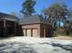 Charming brick home exterior featuring a wooden three-car garage and landscaped front yard at 404 Fairington Dr, Summerville, SC 29485