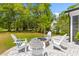 Backyard patio with a stone firepit, and white Adirondack chairs surrounded by a large grassy yard at 481 Woodland Shores Rd, Charleston, SC 29412