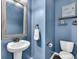Cozy powder room featuring a pedestal sink, framed mirror, and blue walls at 482 Sanders Farm Ln, Wando, SC 29492