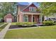 Charming red two-story home with a lush green lawn, manicured bushes, and a detached garage at 4856 Cane Pole Ln, Summerville, SC 29485