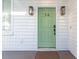 Close-up of a charming light green front door with modern black hardware and stylish exterior lighting at 5 Addison St, Charleston, SC 29403
