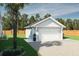 A well-maintained detached garage features a white door, dark roof, and is adjacent to green grass and a palm tree at 5213 Seewee Rd, Awendaw, SC 29429