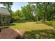 Private backyard featuring mature trees, an established garden bed, and a wooden play set at 667 Shortwood St, Charleston, SC 29412