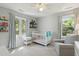 Neutral Bedroom with ample sunlight, white crib, cozy armchair, and views of the outdoors at 667 Shortwood St, Charleston, SC 29412