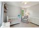 Neutral Bedroom with ample sunlight, white crib, cozy armchair, and views of the outdoors at 667 Shortwood St, Charleston, SC 29412