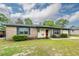 Charming single-story brick home with a well-manicured lawn, mature landscaping, and bright red door at 7655 Ovaldale Dr, North Charleston, SC 29418