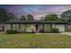 Inviting single-story brick home with a manicured lawn, updated paint, shutters, and attached garage at twilight at 7655 Ovaldale Dr, North Charleston, SC 29418