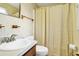 Bright bathroom with a white sink, toilet, and a shower featuring a tan patterned curtain at 7897 Russell Creek Dr, Edisto Island, SC 29438
