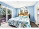 Cozy bedroom featuring blue walls, a comfortable bed with coastal-themed bedding, and sliding glass door access to private deck at 7897 Russell Creek Dr, Edisto Island, SC 29438