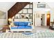 Bright living room with a blue couch, wooden staircase, stylish shelving, and a calming decor at 7897 Russell Creek Dr, Edisto Island, SC 29438