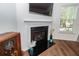 Cozy fireplace with black hearth, mounted television, and decorative vases and antique radio on the hardwood floor at 118 Alpine Rd, Summerville, SC 29485