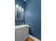 Stylish powder room with bold blue walls, gray vanity, gold hardware and framed mirror at 122 Lucia St, Charleston, SC 29492
