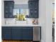 Stylish wet bar featuring navy blue cabinets, a marble countertop, under-counter refrigerator, and decorative lamps at 122 Lucia St, Charleston, SC 29492