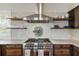 A modern kitchen is equipped with a stainless steel range hood, floating shelves, and a gourmet gas range at 141 Sandy Bend Ln, Summerville, SC 29486