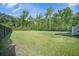 Expansive backyard featuring lush green grass and bordered by mature trees and a black fence at 1489 Brockenfelt Dr, Charleston, SC 29414