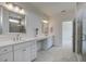Bright bathroom featuring dual vanities, quartz countertop, and a tiled shower with glass door at 1619 Cultivation Ln, Mount Pleasant, SC 29466