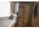 Bright bathroom features a bathtub with tiled surround, a glass door shower, and a decorative window at 1757 Wayah Dr, Charleston, SC 29414