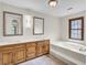 Bright bathroom featuring a soaking tub, double sink vanity with wood cabinets and framed mirrors at 204 Knightsbridge, Charleston, SC 29418