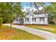 Inviting white home with black shutters and a peaked roof, set amongst lush trees at 205 Tea Farm Rd, Summerville, SC 29483