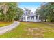 Quaint two-story home with black shutters and a well-manicured lawn, nestled among mature trees at 205 Tea Farm Rd, Summerville, SC 29483