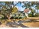 Charming house featuring a light yellow exterior, gray roof, brick chimney, and mature trees at 2178 Fort Pemberton Dr, Charleston, SC 29412