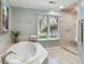 Bathroom with a large soaking tub, a frameless glass shower, and a window overlooking the green landscape at 2355 Andell Way, Seabrook Island, SC 29455