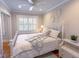 Sunlit bedroom showcases a cozy bed with patterned bedding, a ceiling fan, and decorative wall art for a relaxing ambiance at 24 Archdale St, Charleston, SC 29401